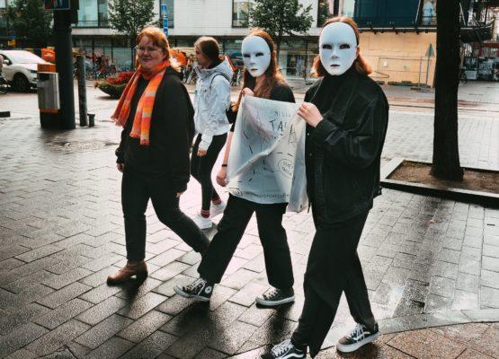 Kaksi ihmistä valkoisissa maskeissa kävelee kadulla.